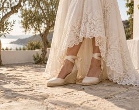 Alpargatas marfil de cuña y cintas al tobillo bajo un vestido de novia con encaje