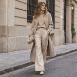 Mujer con prendas beige de distintas texturas en una calle urbana.