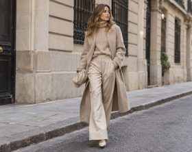 Mujer con prendas beige de distintas texturas en una calle urbana.